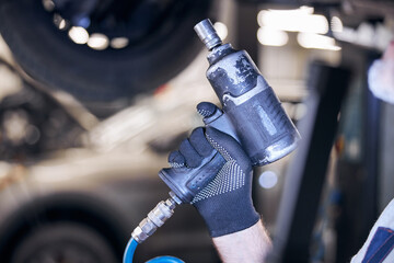 Male auto mechanic hand holding impact wrench