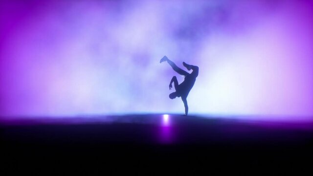 Breakdancer dancing on a stage against colorful spotlights in slow motion