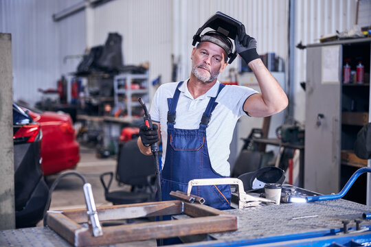 Handsome mechanic with welding torch working in garage