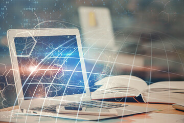 Double exposure of desktop with computer and world map hologram. International data network concept.