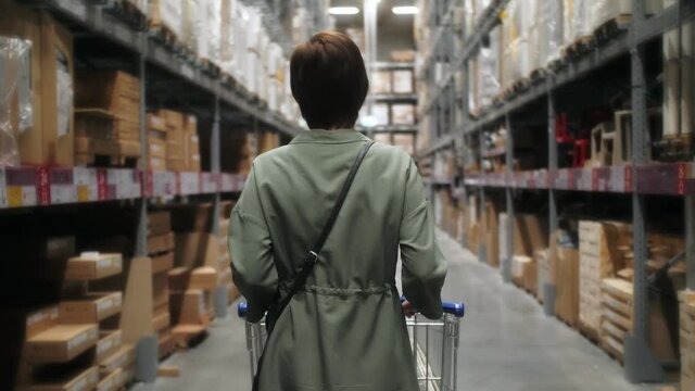 Woman wearing medical face mask and gloves in the shopping mall during pandemic. Customer buys basic necessities.