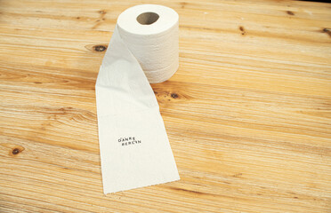 Toilettenpapier auf Holztisch mit Statement auf deutsch zu Berliner Entscheidung Entschluss
