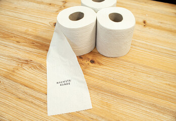 Toilettenpapier auf Holztisch mit Statement auf deutsch zu Berliner Entscheidung Entschluss