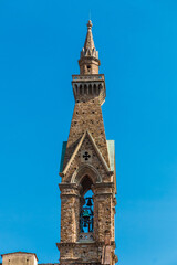 Great close-up view of the slender bell tower of the Basilica di Santa Croce in Florence. The tower with single-lancet windows, frames and a cusp lantern was built with typical Florentine limestone.