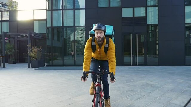 Food delivery rider on his bicycle. Image of a middle age man at work in the city center. Delivering pizza and burgers at home with the thermal backpack