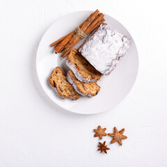 Traditional Christmas stollen cake on white background. Fruit bread with nuts, spices and dried fruit. Top view. Copy space.