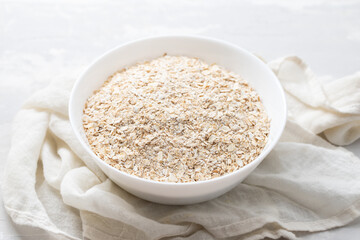 dry oat in the white bowl on ceramic background