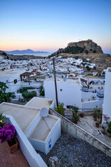 The small town of Lindos hides behind the mighty rock of the acropolis separating two coves with...