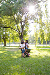 Happy dad meeting with two children after military mission trip, hugging kids on grass in park. Sunshine background. Family reunion or returning home concept