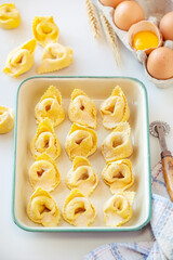 Fresh homemade uncooked  Italian ravioli on a tray sprinkled with flour