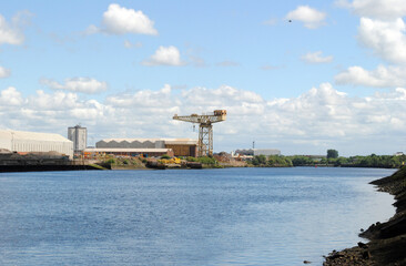 Fototapeta na wymiar River View with Industrial Buildings & Crane on Sunny Day