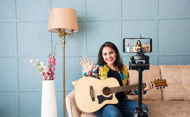Indian young female musician playing keyboard or guitar or flute in front of camera