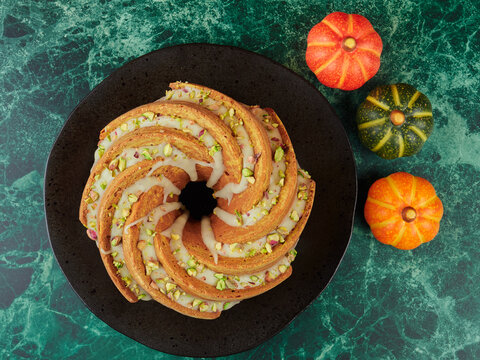 Homemade pumpkin bundt cake drizzled with an orange glaze and sprinkled with chopped pistachios
