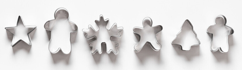 Obraz premium Banner of Christmas-themed cookie cutters for gingerbread in raw on white background. Xmas concept. Top view, flat lay.