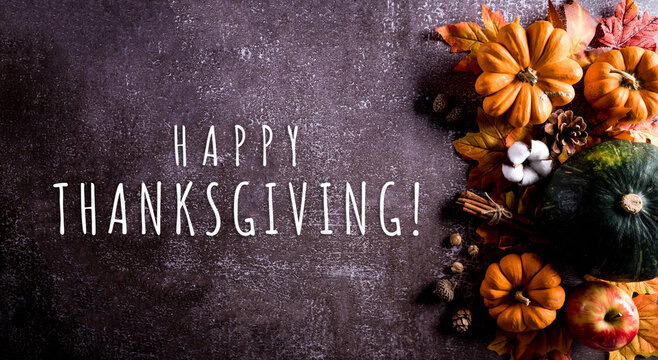 Thanksgiving background decor from dry leaves and pumpkin on dark stone  background. Flat lay, top view with copy space