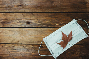 Mascarilla con hoja de oto&ntilde;o en un fondo de madera. coronavirus