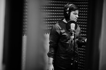 Young asian singer man with microphone recording song in record music studio.