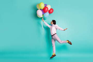 Portrait of jumping young man hold colorful helium balloons wear formal outfit yellow socks...