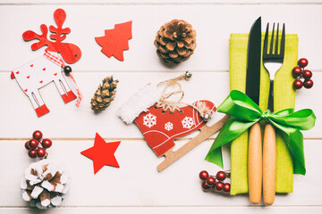 Top view of fork and knife on napkin on wooden background. Different christmas decorations and toys. Close up of New Year dinner concept