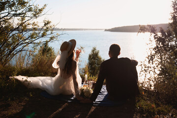 Fototapeta premium girl and boyfriend drink champagne, look at the sea, waiting for the sunset