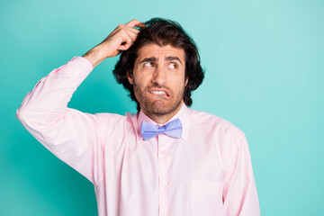 Photo of thoughtful curly man dressed pink outfit arm head look empty space bite lip isolated teal...