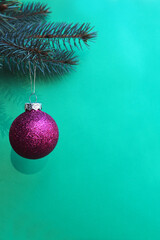 round bright shiny pink toy hanging on a tree branch on a green background . symbol of Christmas