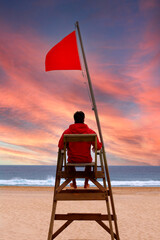 Lifeguard sitting on a high chair looking at the sea
