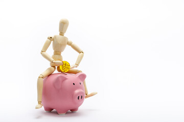 豚の貯金箱に跨って、コインを入れようとする、木の人形。
