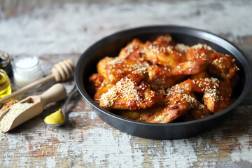 Baked chicken wings with sesame seeds in a skillet. Junk food. Delicious buffalo wings.