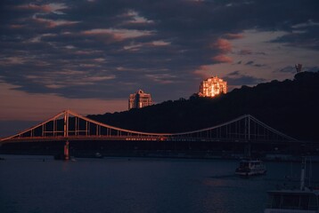 Evening sky, pink sky and dark blue clouds, buildings, bridge and trees, urban aesthetics, river