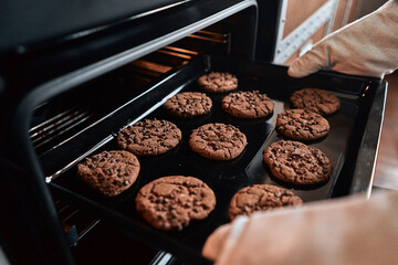 Chef in oven-gloves preparing pastries in the oven