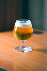Lager beer in glass on wooden table at home.