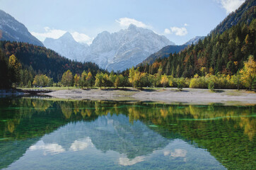 Autumn alps mountains in day light reflected in calm waters of lake.