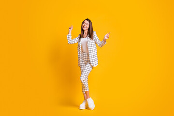 Full length body size photo of dancing woman wearing round eyeglasses enjoying music isolated on bright yellow color background