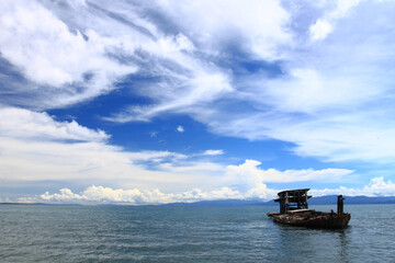 Wreck ship on the beach with cloudy blue sky on the background