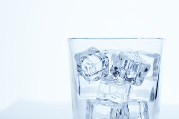 glass with ice cubes on white background