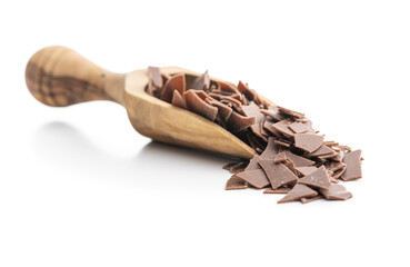 Grated dark chocolate in wooden scoop. Chocolate flakes isolated on white background.