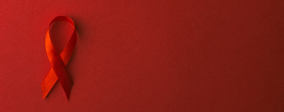 Red bow ribbon symbol HIV, AIDS cancer awareness with shadows, studio shot isolated on red background, Healthcare medicine concept, World AIDS Day