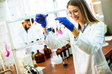 Young female scientist examining liquid in biochemical lab