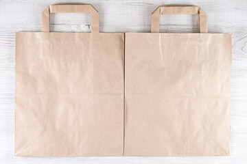two brown ecological paper bag on a white wooden table. Place for your logo.
