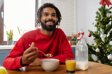 Joyful african american man eating cereal while having breakfast