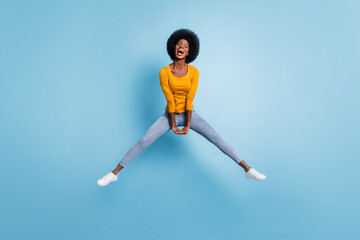 Fototapeta na wymiar Photo portrait full length of energetic girl jumping up with hands down together isolated on pastel blue colored background