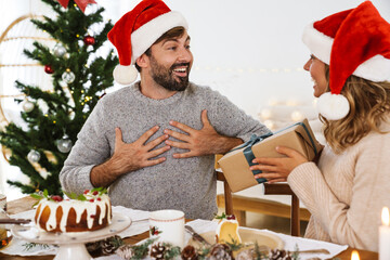 Happy woman giving gift to his boyfriend while having Christmas dinner