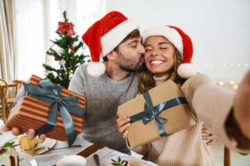Fototapeta premium Nice excited couple taking selfie while having Christmas dinner