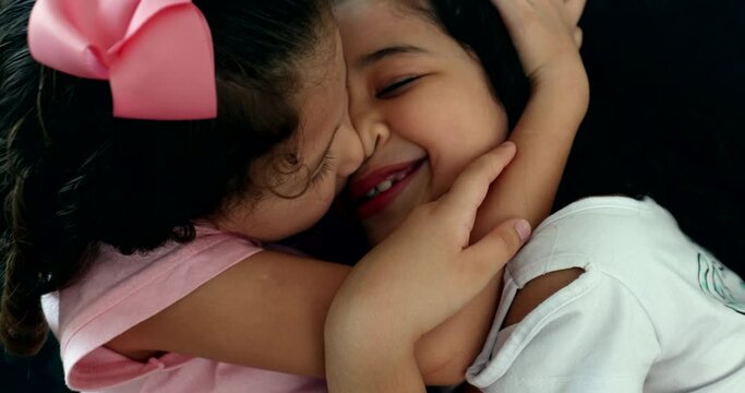 Children hug, two little sisters showing love, sibling kissing little sister kid