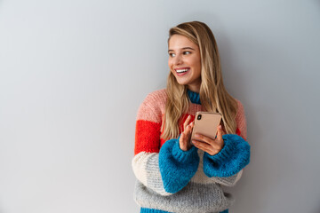 Naklejka premium Smiling young woman using smartphone