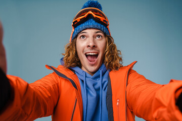Handsome happy sportsman taking selfie with snowboard