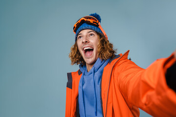 Handsome happy sportsman taking selfie with snowboard
