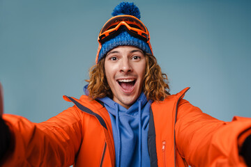 Handsome happy sportsman taking selfie with snowboard