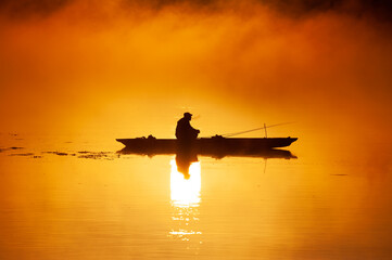 Fototapeta na wymiar Silhouette Fisherman Fishing Rod Wooden Boat Sunrise Fog River